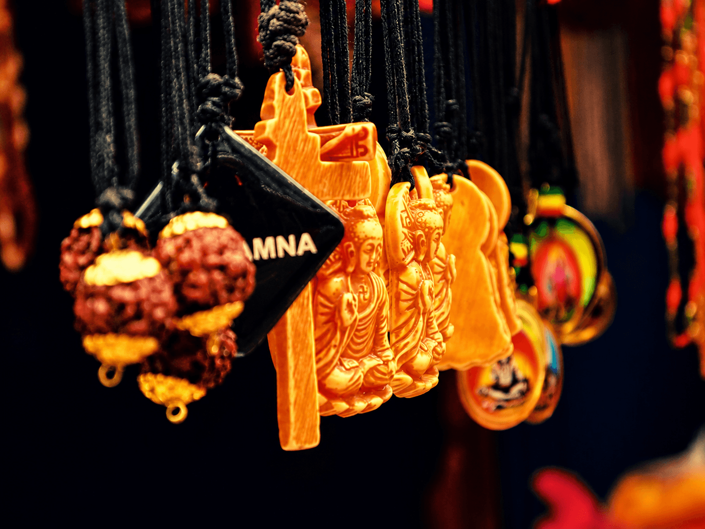 Carved Buddha pendants and rudraksha beads hanging at a market stall