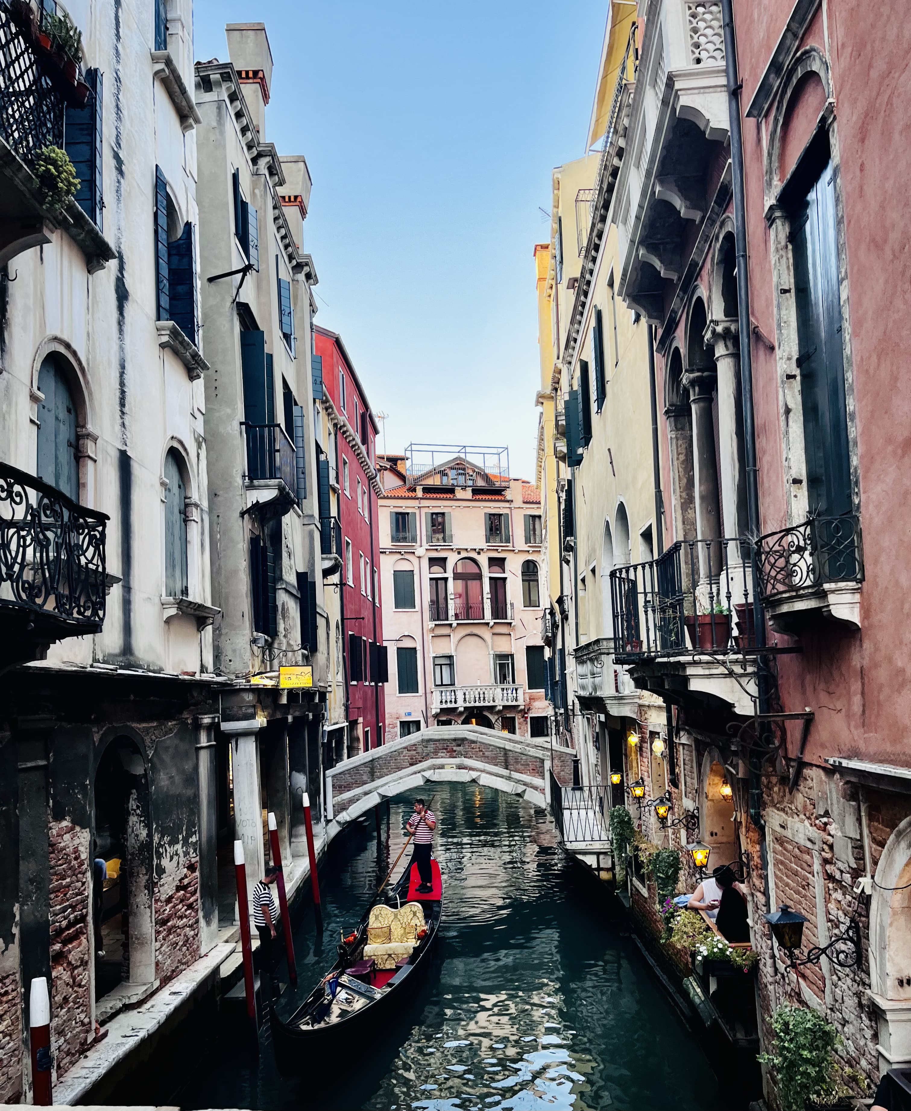 A gondolier steering a gondola through a narrow Venice canal